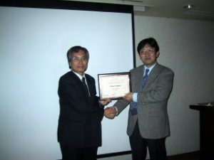 賞を代理で受け取って頂いた中野先生から， LEOS Japan Chapter Chair保立先生に盾が渡されました．